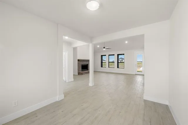 a view of an empty room with a window and kitchen view