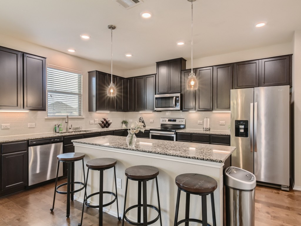 a kitchen with granite countertop a center island stainless steel appliances cabinets and a counter top space
