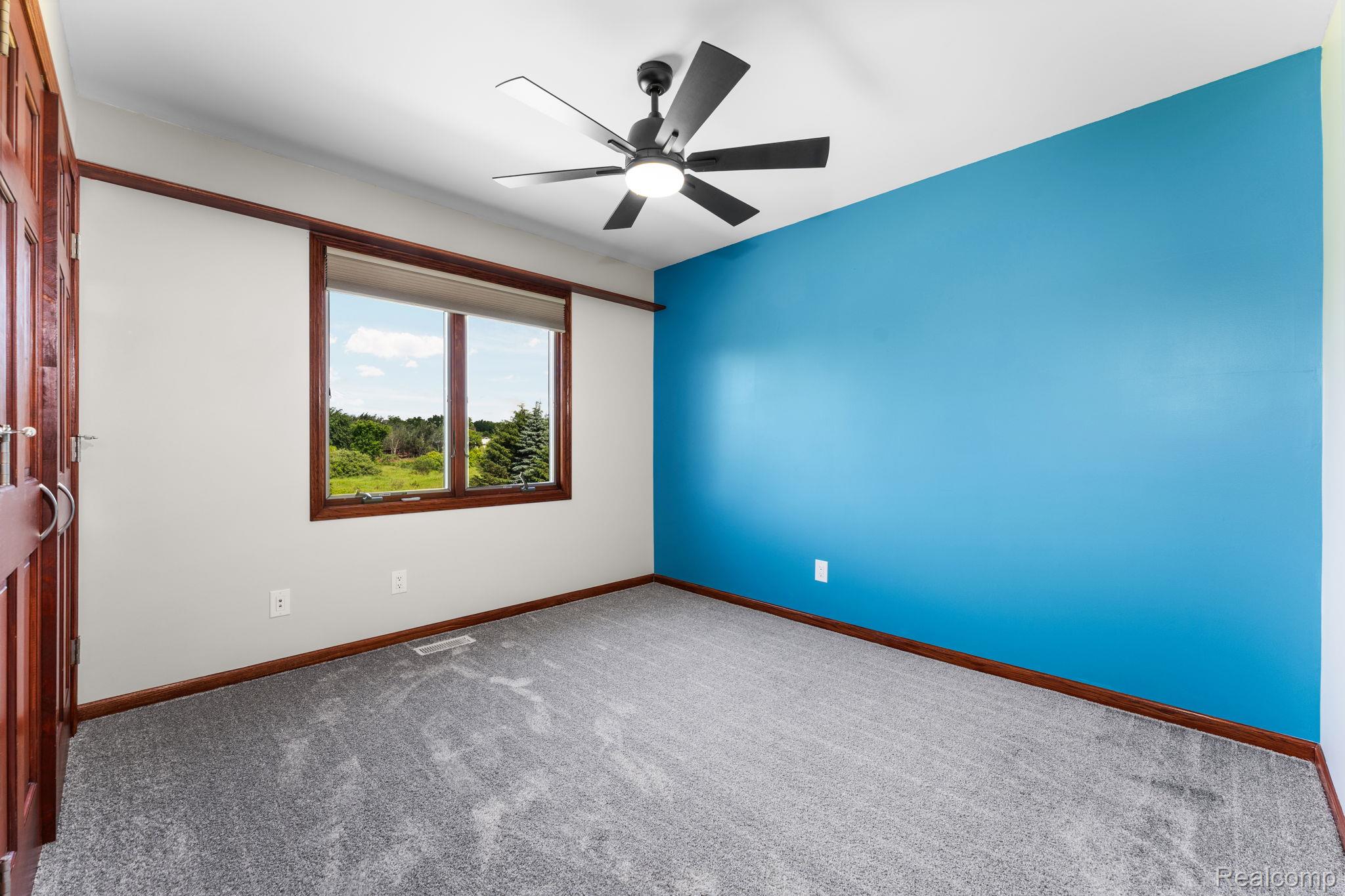 2381 Burke Road Fowlerville, MI 48836 - Photo 19 of 31 Bedroom 2, neutral wall tones with a vibrant accent wall with ceiling fan