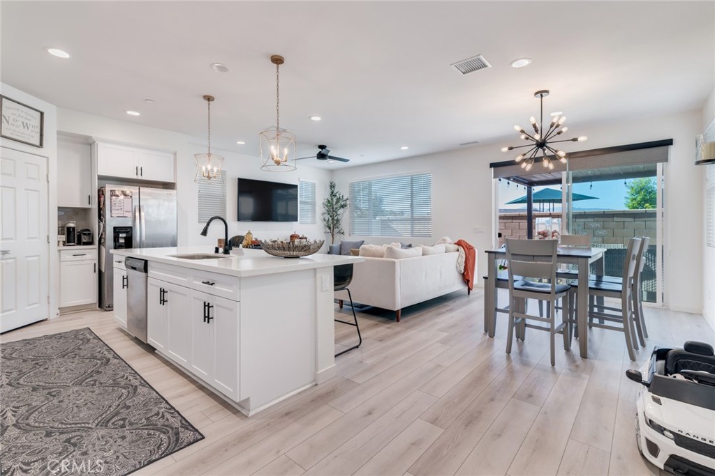4247 Bravado Court Riverside, CA 92505 - Photo 5 of 33 a kitchen island with stainless steel appliances kitchen island granite countertop a stove a sink a dining table and chairs with wooden floor