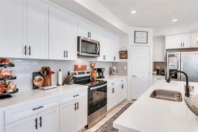 a kitchen with white cabinets and stainless steel appliances