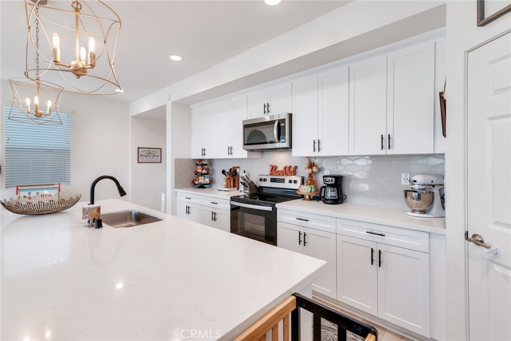4247 Bravado Court Riverside, CA 92505 - Photo 8 of 33 a kitchen with white cabinets and stainless steel appliances