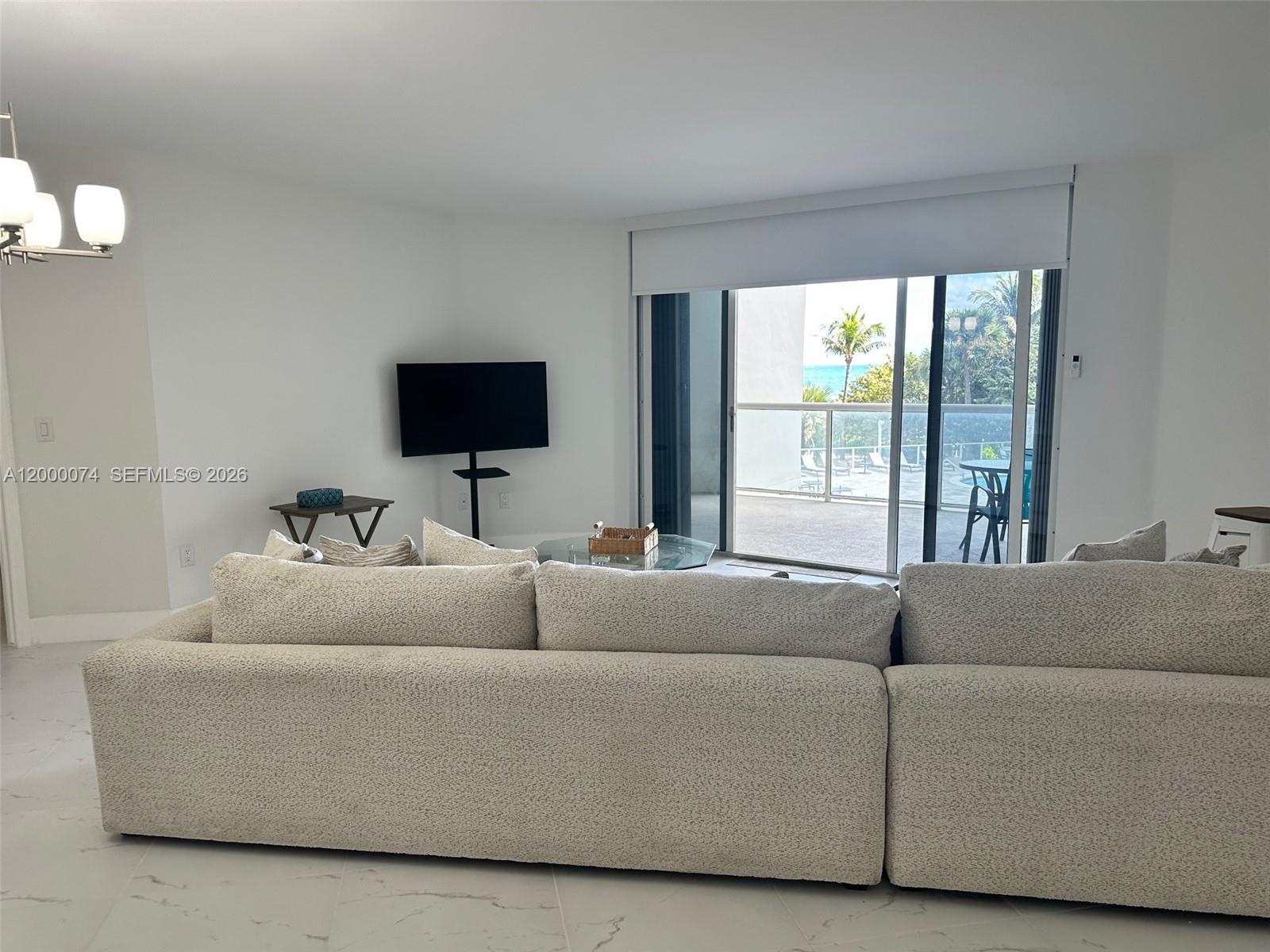 8925 Collins Avenue, Unit 2J Surfside, FL 33154 - Photo 14 of 63 a living room with furniture and a flat screen tv