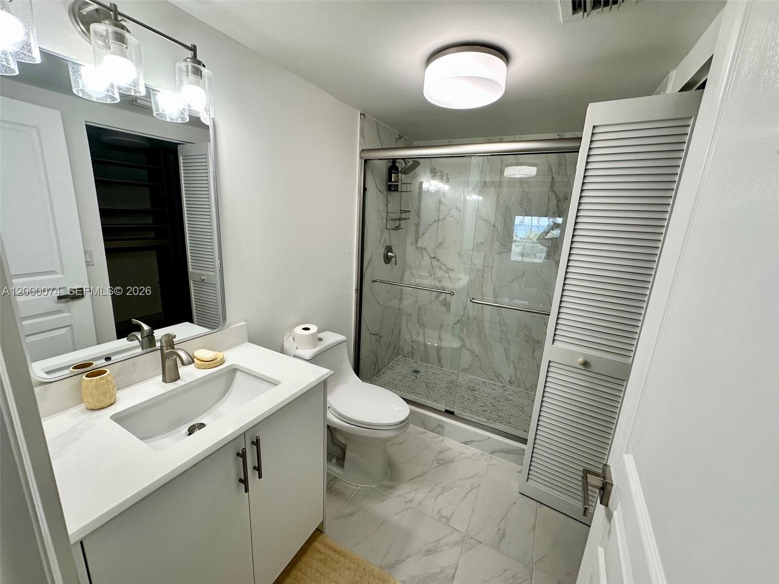 8925 Collins Avenue, Unit 2J Surfside, FL 33154 - Photo 34 of 63 a bathroom with a sink a toilet a mirror and shower