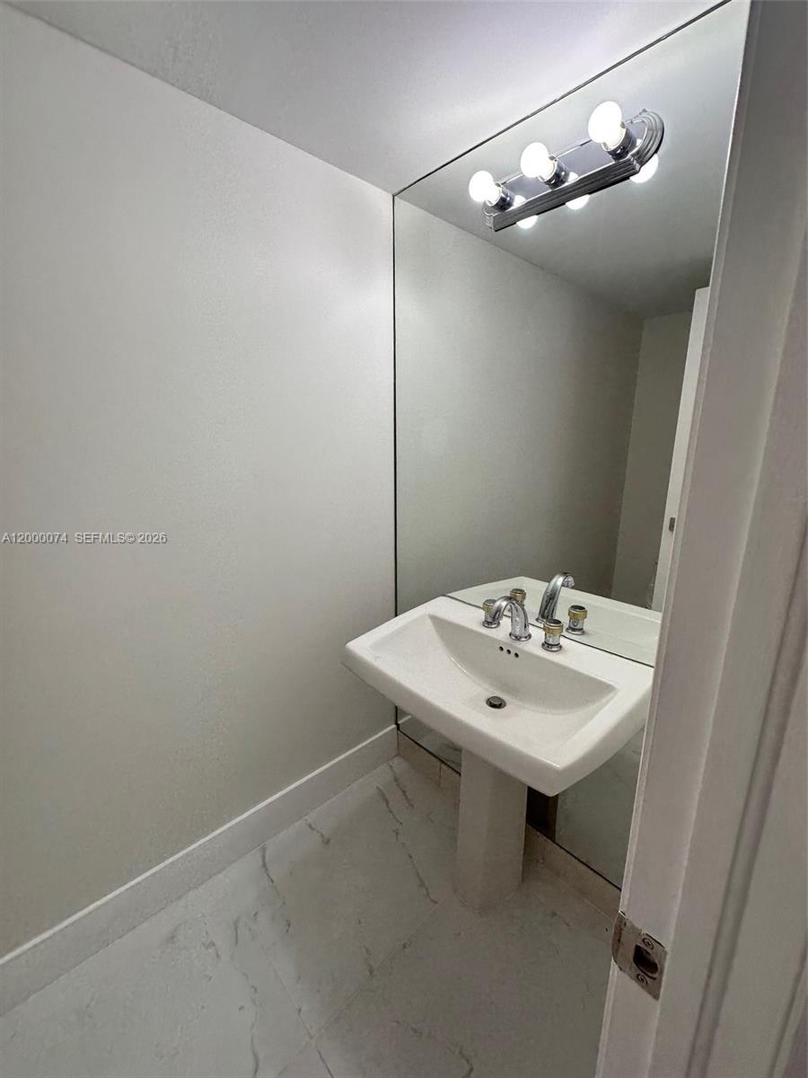8925 Collins Avenue, Unit 2J Surfside, FL 33154 - Photo 9 of 63 a bathroom with a sink a mirror and vanity