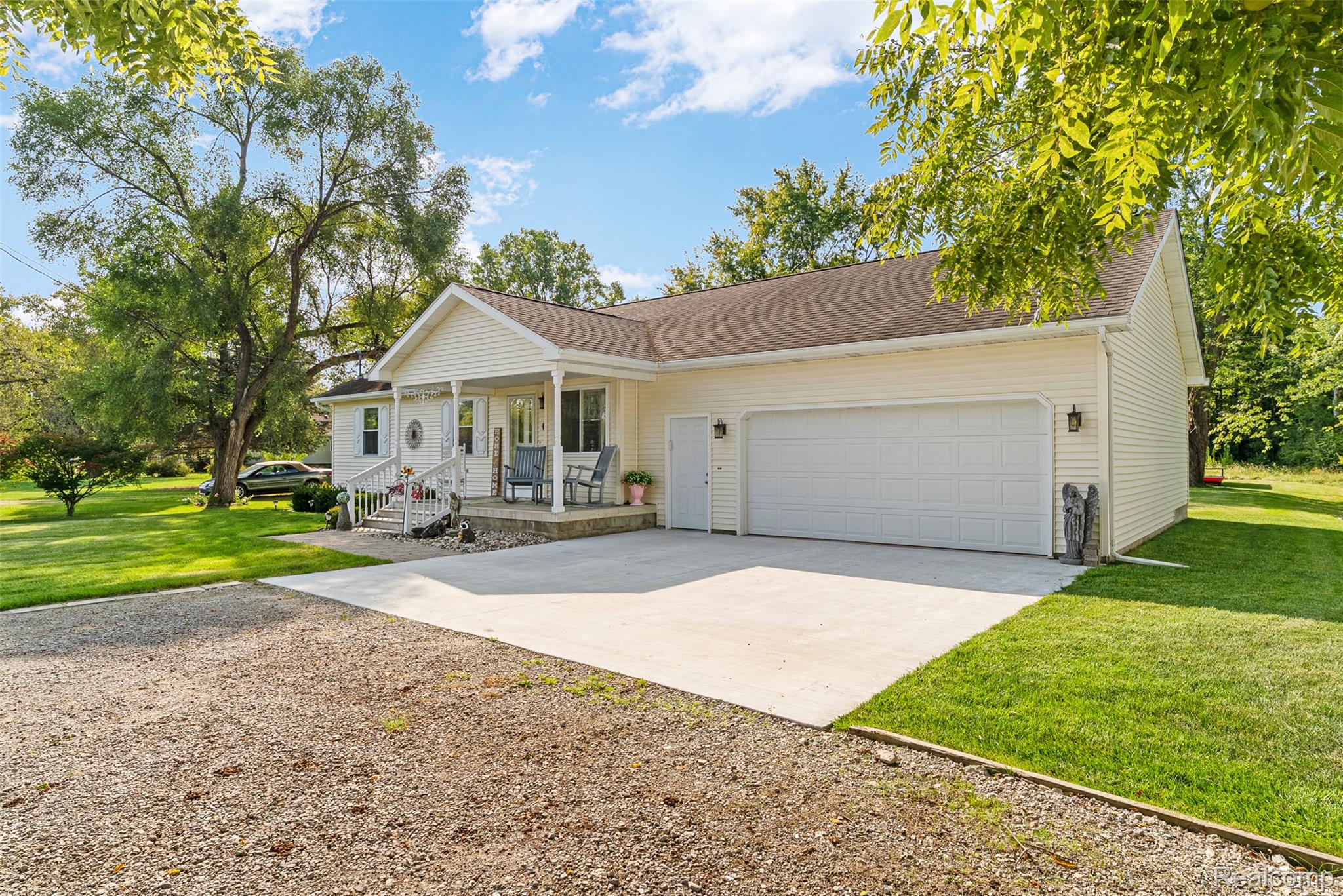 Ranch-style house featuring driveway, a front lawn, covered porch, and a garage