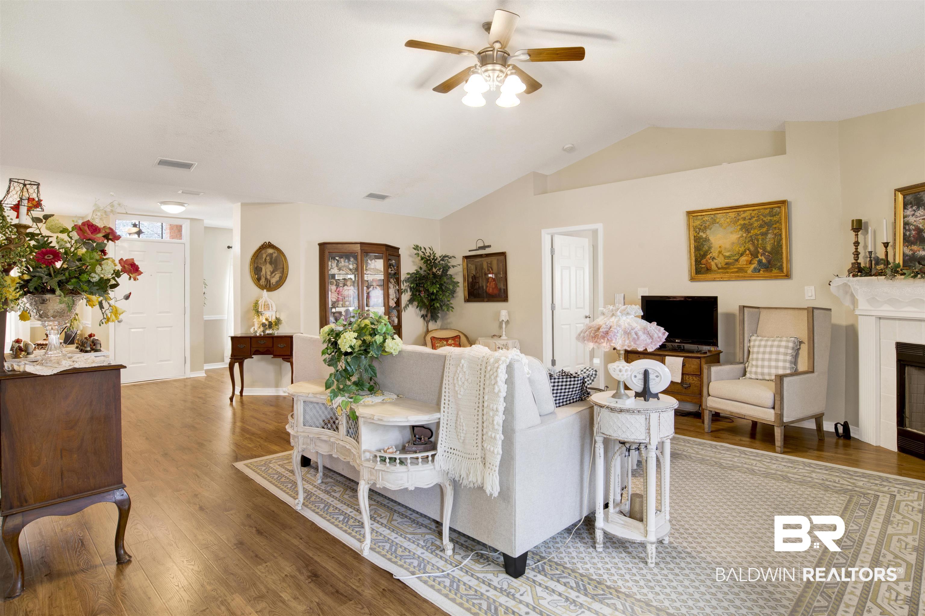11697 Balsam Court Daphne, AL 36527 - Photo 11 of 31 Living room featuring ceiling fan, wood-type flooring, vaulted ceiling, and a tile fireplace