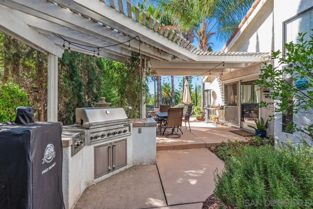 12904 Stone Canyon Road Poway, CA 92064 - Photo 51 of 72 a view of a patio with table and chairs potted plants and floor to ceiling window