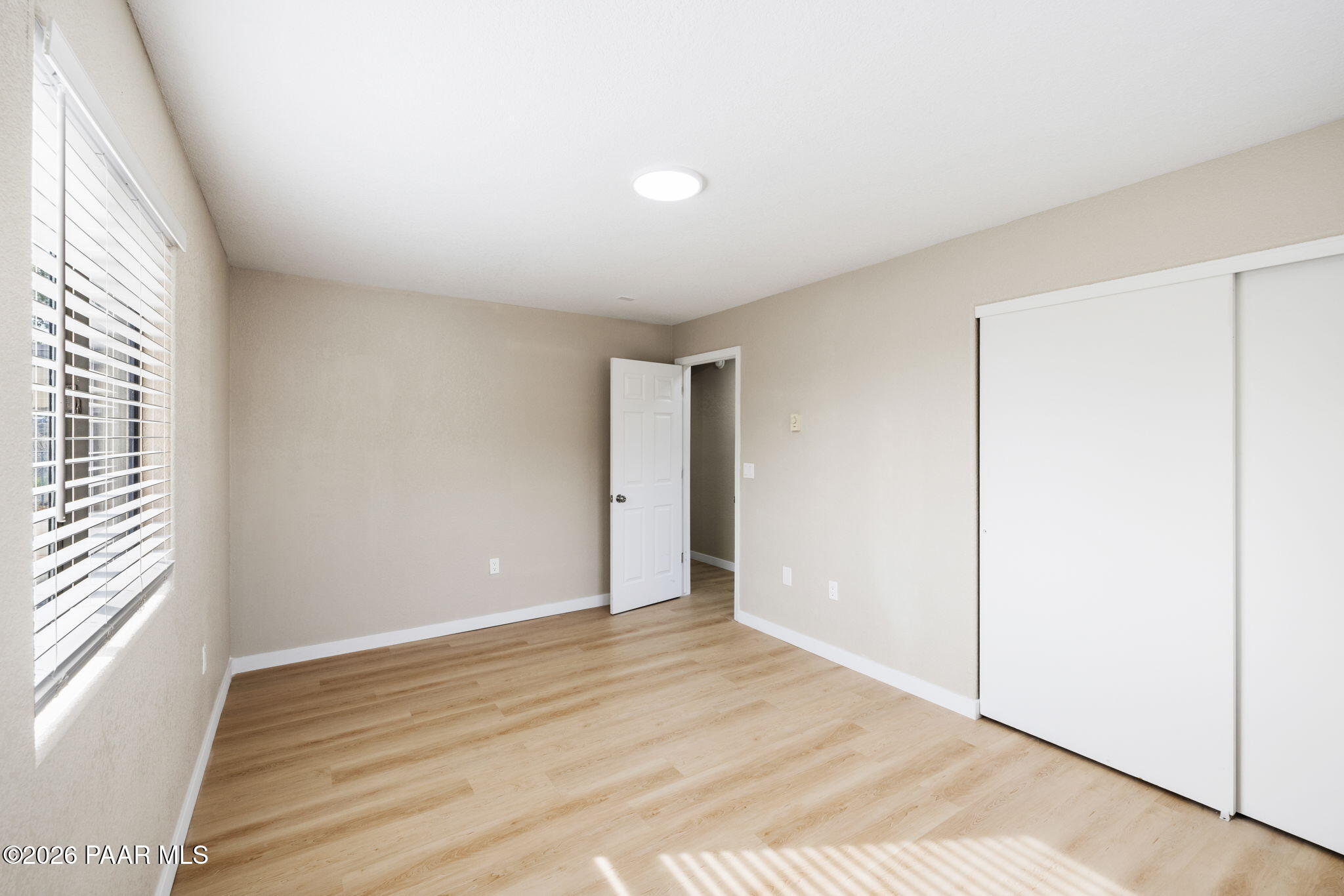 20102 East Antelope Road Mayer, AZ 86333 - Photo 15 of 24 an empty room with wooden floor and windows with curtains