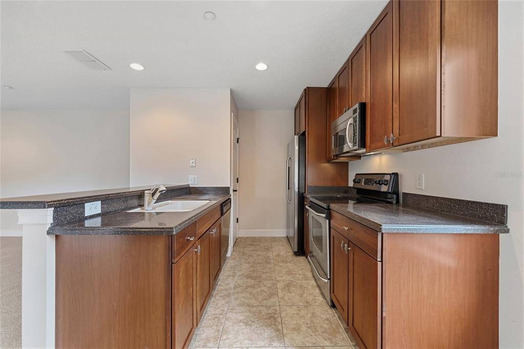 1027 Juel Street Orlando, FL 32814 - Photo 63 of 78 a kitchen with stainless steel appliances granite countertop a sink a stove and a refrigerator
