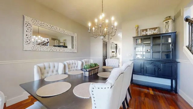 a very nice looking dining room with furniture a chandelier and wooden floor