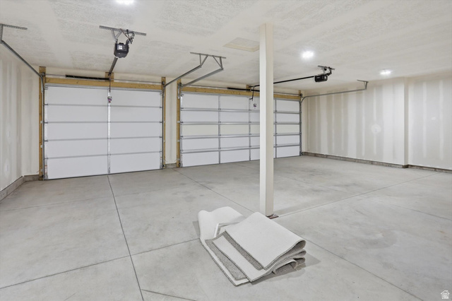 1315 West 3200 South, Unit 17 Perry, UT 84302 - Photo 50 of 58 Spacious two-car garage featuring concrete flooring, two white panel garage doors, and overhead lighting