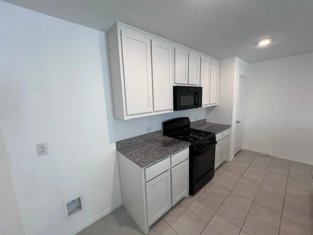 a kitchen with granite countertop sink stove and cabinets