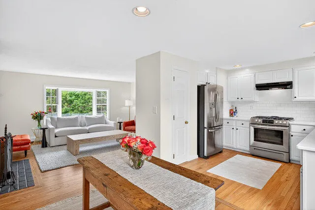 a kitchen with stainless steel appliances kitchen island granite countertop a refrigerator stove top oven dining table and chairs