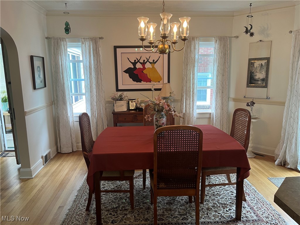 134 Ridgewood Drive Youngstown, OH 44512 - Photo 7 of 29 Dining space featuring light wood-style flooring, arched walkways, ornamental molding, and a chandelier