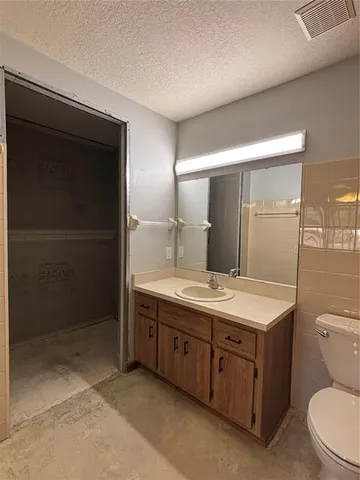 a bathroom with a granite countertop sink a toilet a mirror and shower