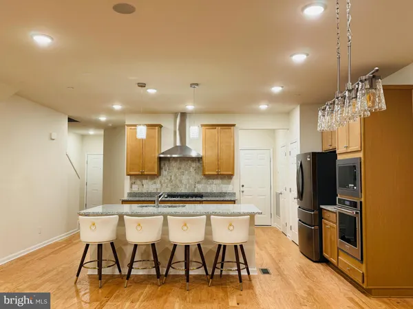 a kitchen with stainless steel appliances kitchen island granite countertop a kitchen island a stove a dining table and chairs