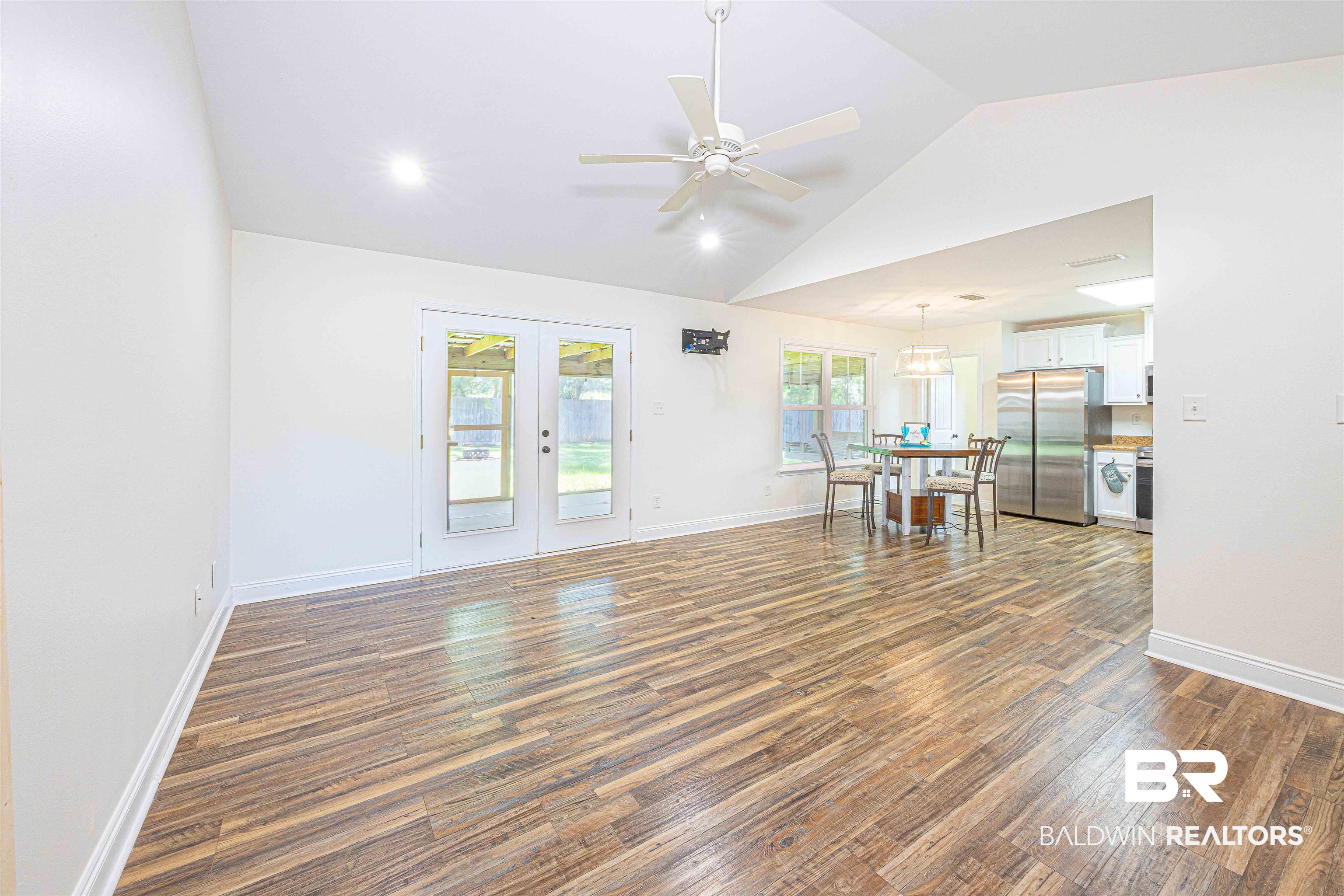 18675 Explorer Drive Loxley, AL 36551 - Photo 5 of 42 Unfurnished living room featuring wood finished floors, vaulted ceiling, french doors, ceiling fan, and baseboards