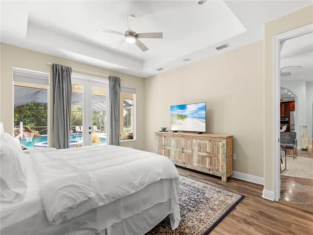a bedroom with a large bed a chandelier and windows
