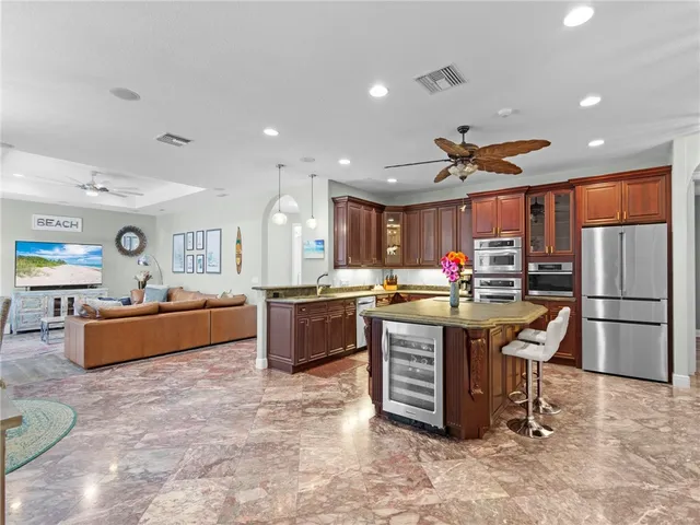 a large kitchen with stainless steel appliances a stove a sink dishwasher a refrigerator and a dining table with wooden cabinet