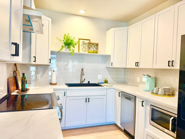 a kitchen with stainless steel appliances granite countertop a sink and dishwasher with white cabinets