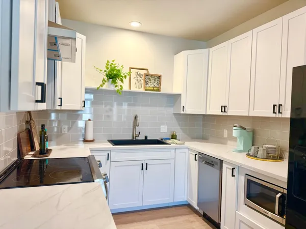 a kitchen with granite countertop a sink stainless steel appliances and cabinets