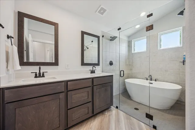 a spacious bathroom with a double vanity sink mirror and bathtub