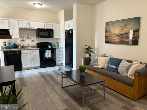 a living room with furniture a flat screen tv and kitchen view