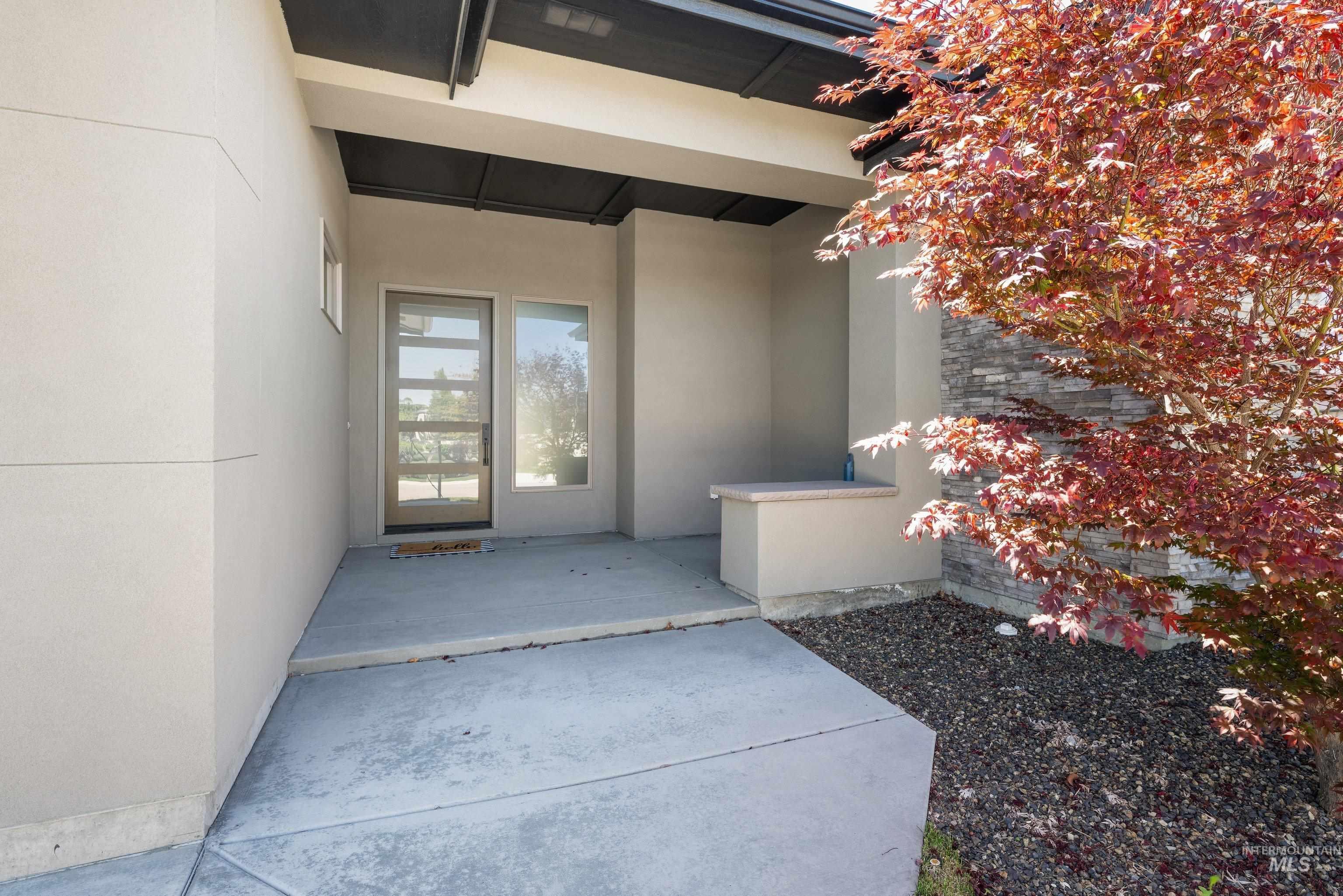 4447 East Copper Point Drive Meridian, ID 83642 - Photo 3 of 41 Modern entry featuring a full-light door with frosted glass panels, an adjacent sidelight, and a built-in stucco bench