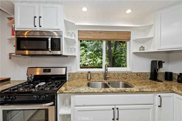 a kitchen with granite countertop a sink stainless steel appliances and cabinets