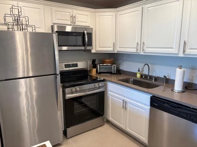 a kitchen with stainless steel appliances granite countertop a refrigerator a stove a sink and a microwave