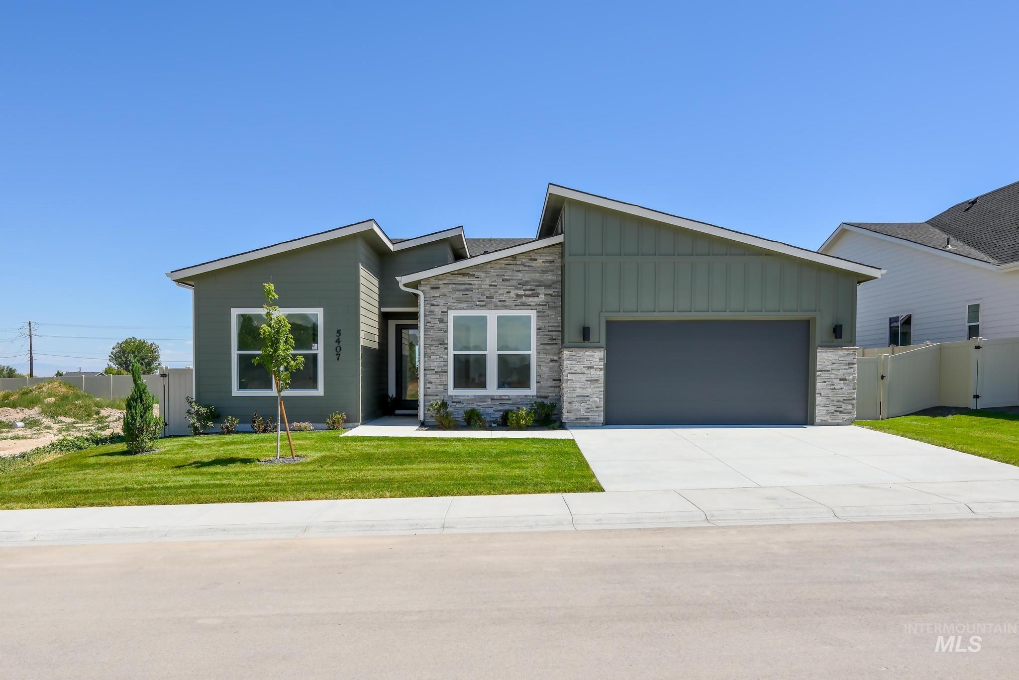 View of front of house with board and batten siding, a garage, driveway, and stone siding