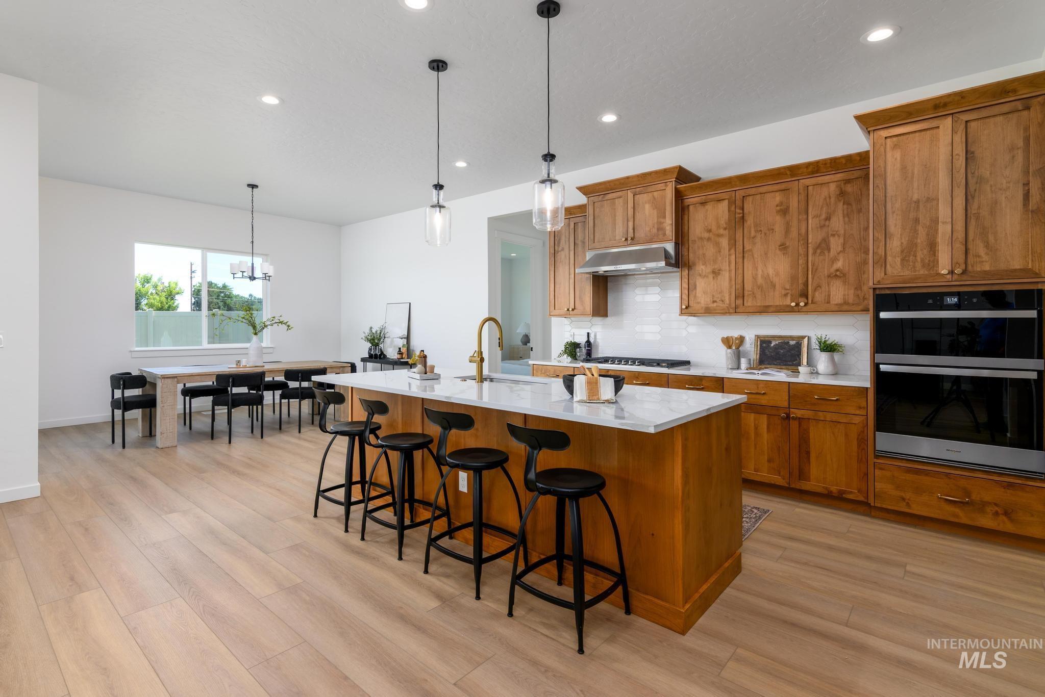 5407 Sparky Avenue Caldwell, ID 83607 - Photo 9 of 41 Kitchen featuring brown cabinetry, backsplash, decorative light fixtures, and recessed lighting