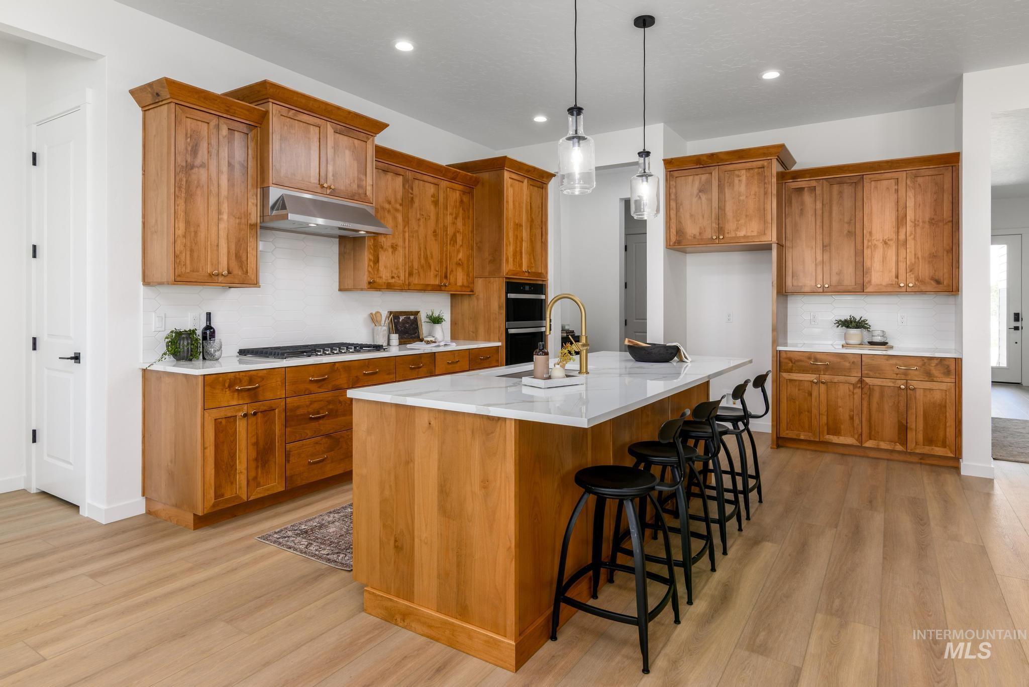 5407 Sparky Avenue Caldwell, ID 83607 - Photo 10 of 41 Kitchen featuring backsplash, brown cabinetry, a breakfast bar area, hanging light fixtures, and recessed lighting