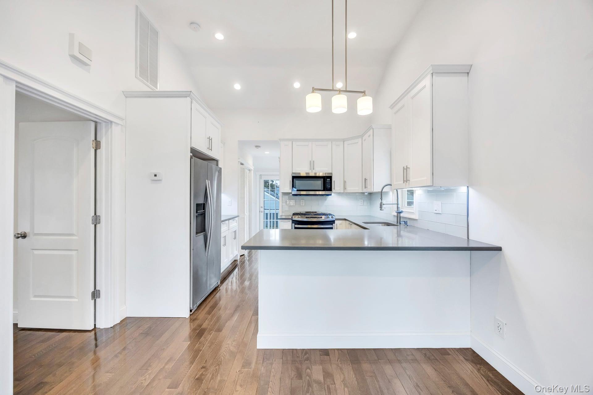 21 Ireland Place Copiague, NY 11726 - Photo 14 of 26 a kitchen with stainless steel appliances granite countertop a sink a stove a refrigerator and island with wooden floor