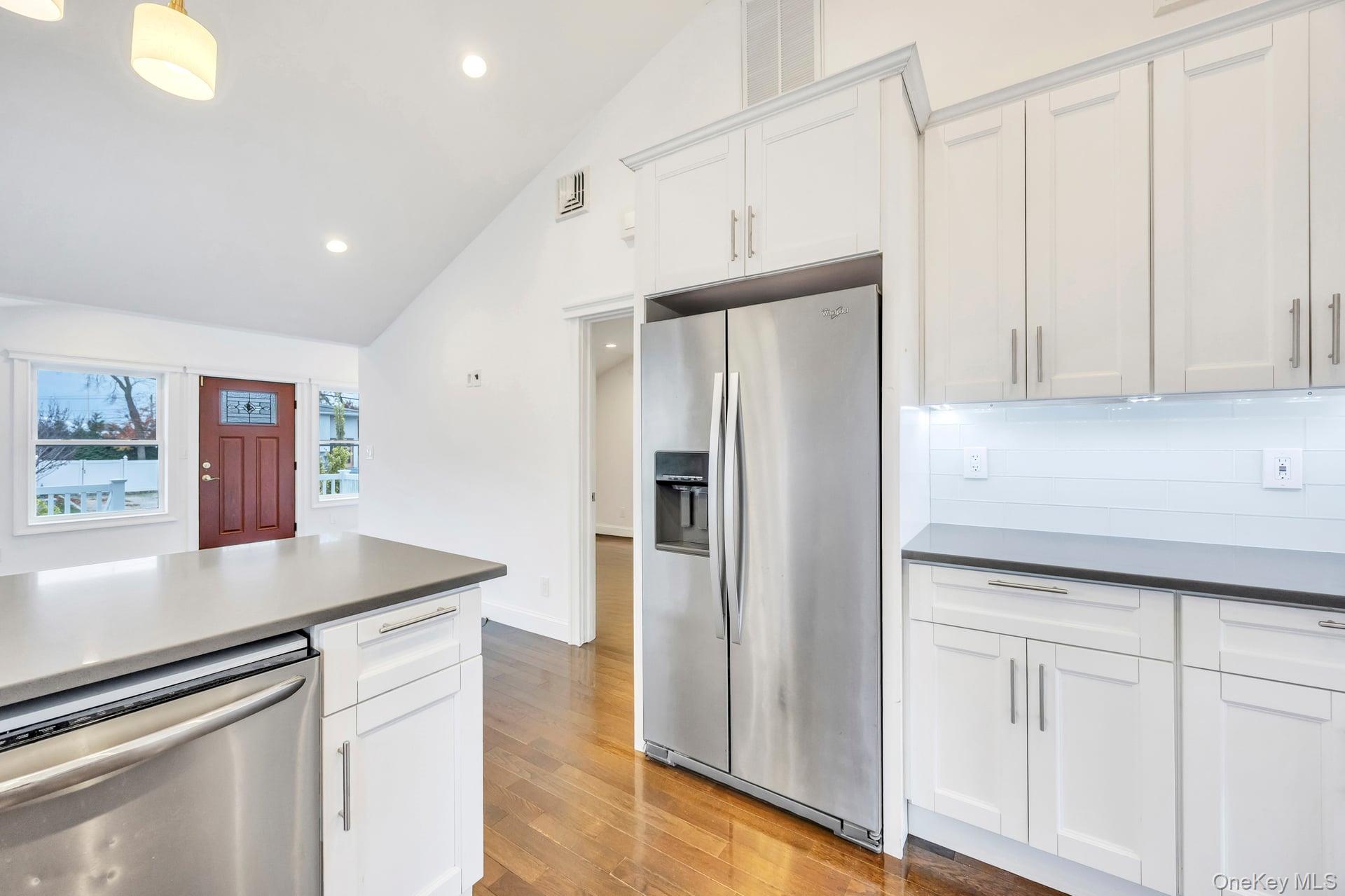 21 Ireland Place Copiague, NY 11726 - Photo 19 of 26 a kitchen with stainless steel appliances granite countertop a refrigerator a sink and white cabinets with wooden floor