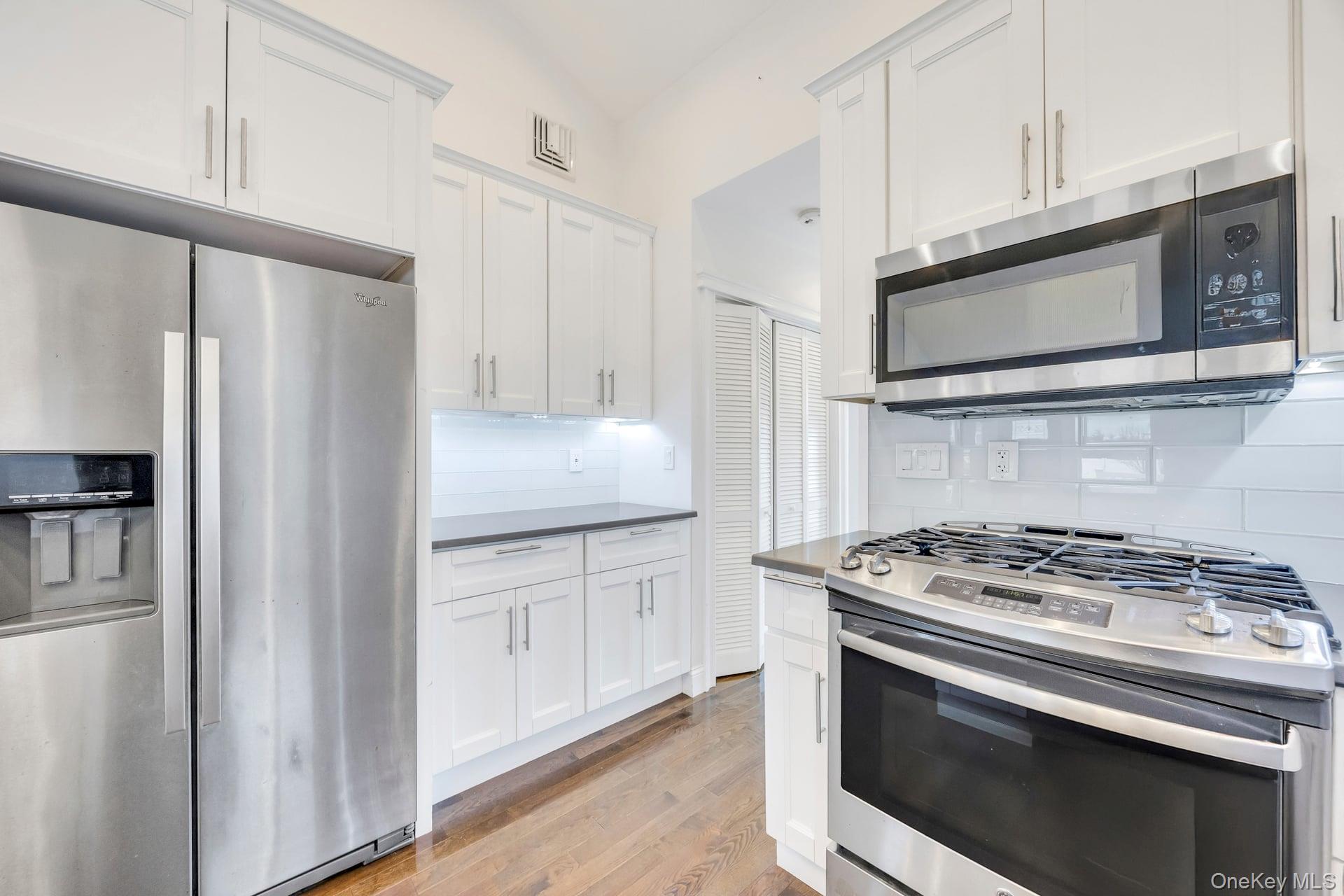 21 Ireland Place Copiague, NY 11726 - Photo 20 of 26 a kitchen with stainless steel appliances white cabinets a stove top oven and a refrigerator
