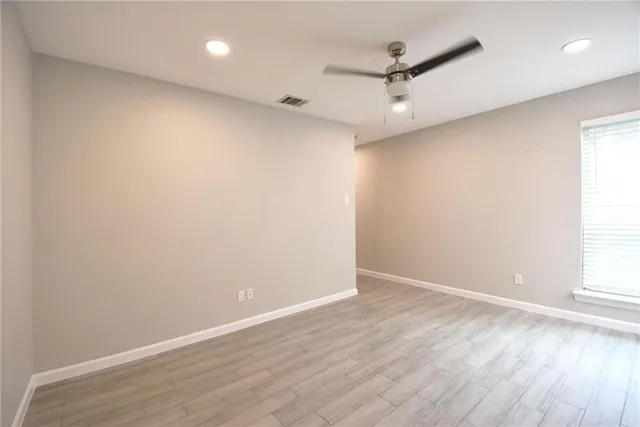 an empty room with wooden floor and a ceiling fan