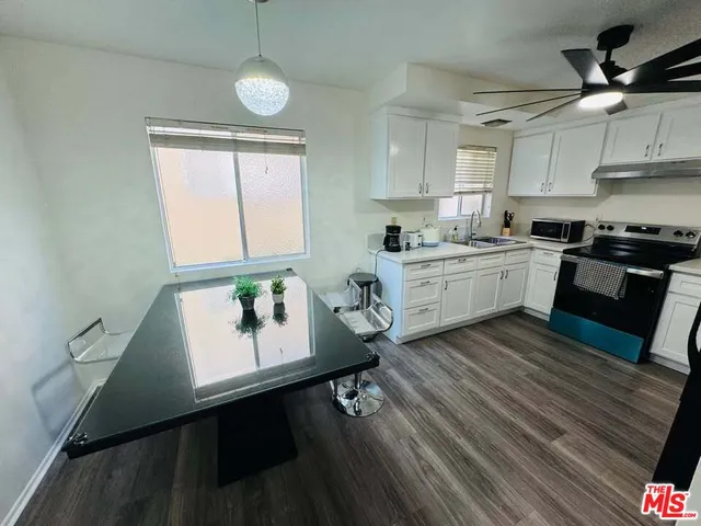 a kitchen with kitchen island granite countertop a stove a sink a dining table and chairs with wooden floor