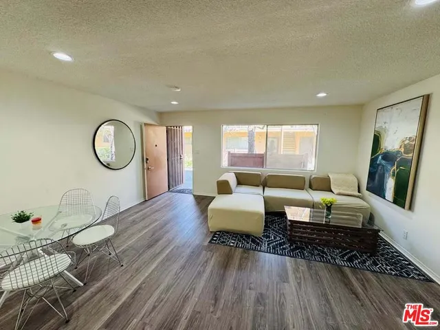 a living room with furniture a rug a lamp and a large window