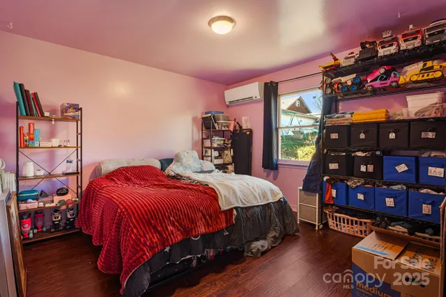 a bedroom with a bed a books dresser and a large window