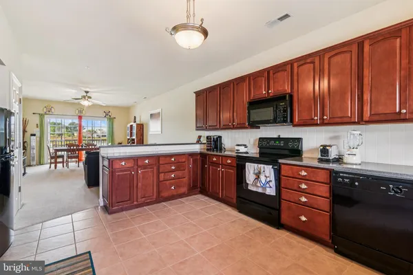 a kitchen with kitchen island granite countertop wooden cabinets a counter top space a sink and appliances