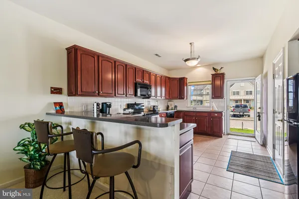 a kitchen with stainless steel appliances granite countertop a refrigerator a sink dishwasher a stove top oven a large island with wooden cabinets and floor