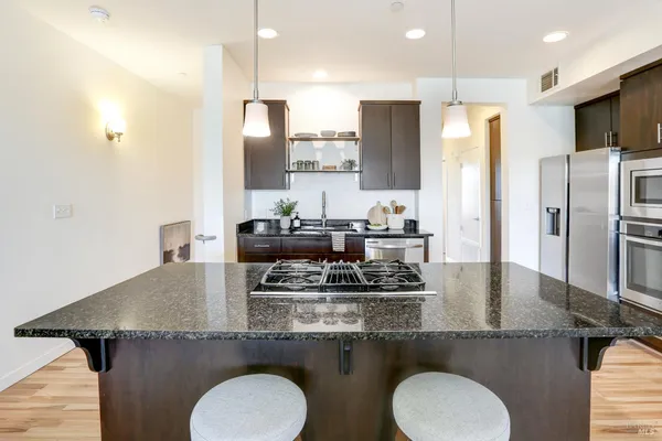 a kitchen with a granite countertop kitchen island stainless steel appliances a sink stove and refrigerator
