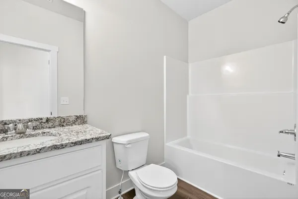 a bathroom with a granite countertop toilet a sink and a bathtub