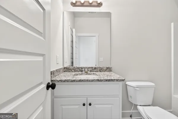 a bathroom with a granite countertop sink toilet and mirror