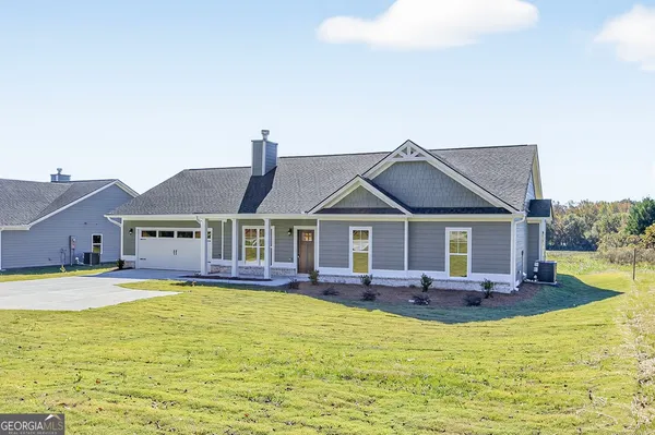a front view of house with yard and trees in the background
