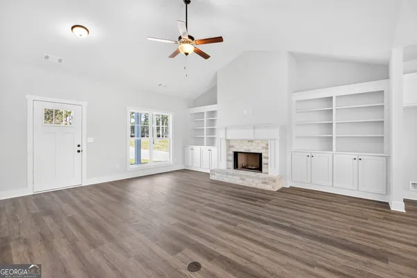 a view of an empty room with wooden floor fireplace and a window