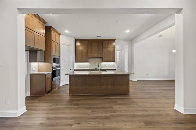 a living room with stainless steel appliances kitchen island granite countertop a living room view and wooden floor