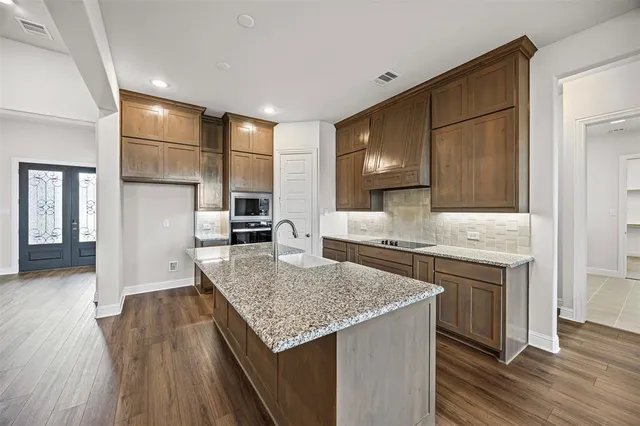 a kitchen with kitchen island granite countertop a sink and wooden cabinets